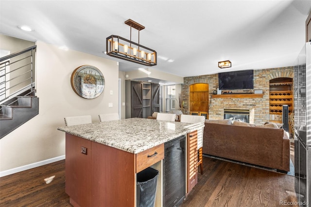 kitchen featuring a center island, a brick fireplace, wine cooler, dark hardwood / wood-style flooring, and pendant lighting