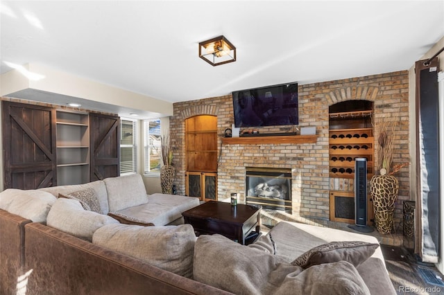 living room with a barn door, built in features, and a brick fireplace