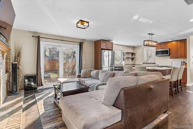 living room featuring dark hardwood / wood-style floors and a brick fireplace