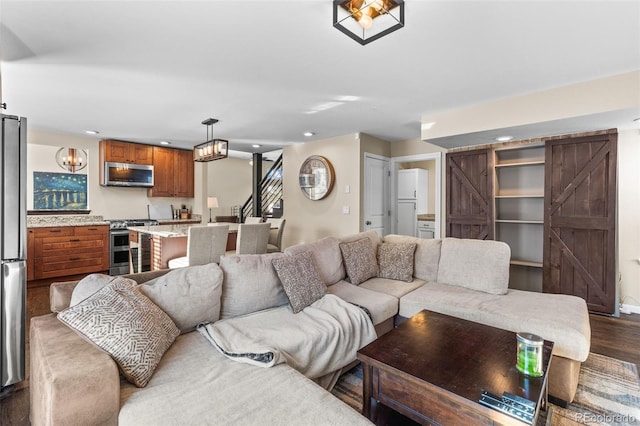 living room with a barn door and dark wood-type flooring