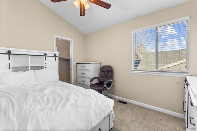 bedroom featuring a walk in closet, light colored carpet, vaulted ceiling, ceiling fan, and a closet