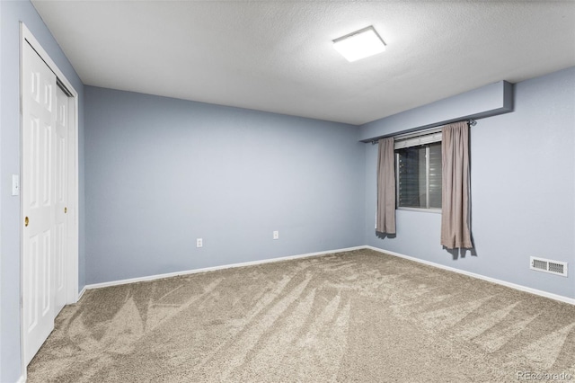 spare room featuring carpet floors and a textured ceiling