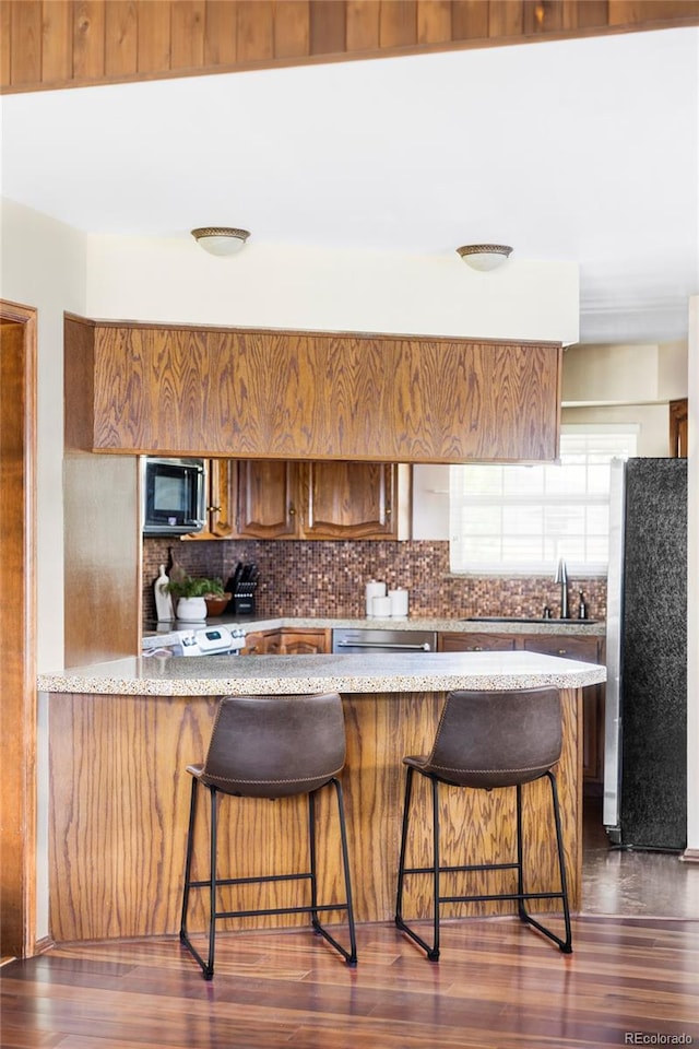 9867 W Berry Dr, Littleton, CO 80123 - kitchen with stainless steel appliances, a sink, decorative backsplash, and a breakfast bar