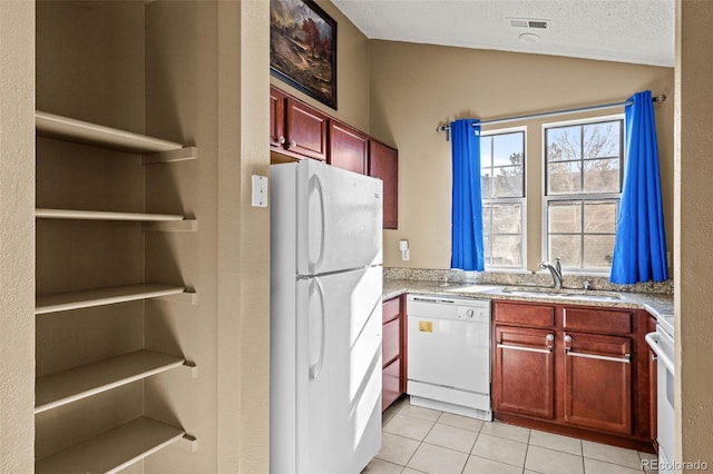 kitchen with dark brown cabinets, light countertops, a sink, white appliances, and vaulted ceiling