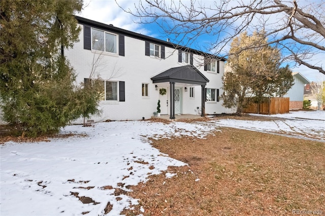 colonial home featuring fence and brick siding