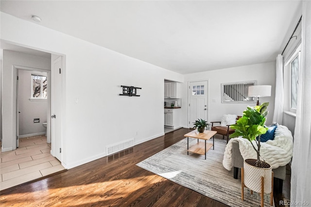 living room with visible vents, baseboards, and wood finished floors