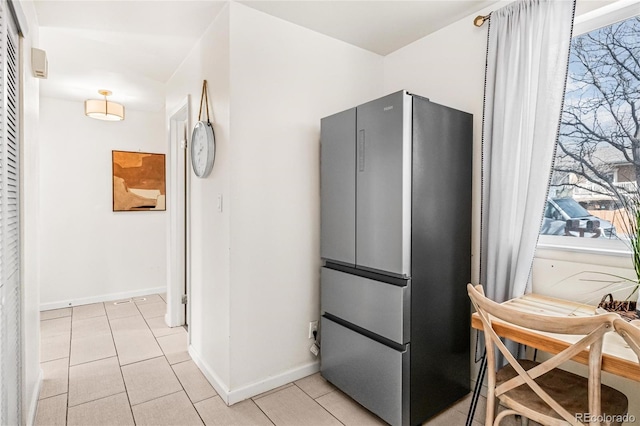 kitchen featuring freestanding refrigerator, baseboards, and light tile patterned floors