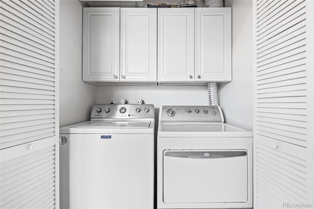 clothes washing area featuring washing machine and dryer and cabinet space