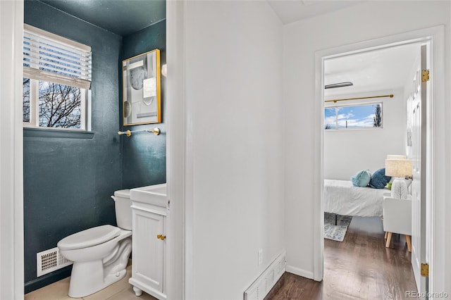 bathroom with toilet, ensuite bathroom, visible vents, and baseboards