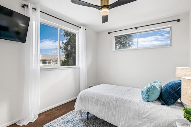 bedroom featuring multiple windows, ceiling fan, baseboards, and wood finished floors