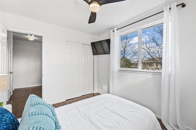 bedroom with ceiling fan, a closet, dark wood finished floors, and baseboards