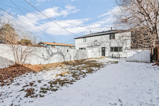 snow covered house featuring fence