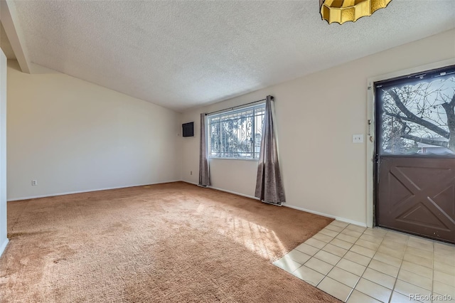 foyer entrance featuring light carpet, light tile patterned floors, and a textured ceiling