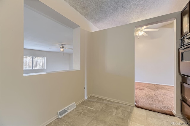 empty room with visible vents, ceiling fan, a textured ceiling, and baseboards