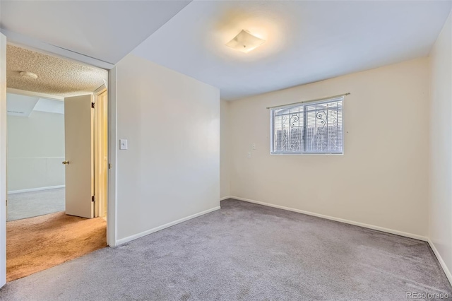 carpeted spare room featuring baseboards and a textured ceiling