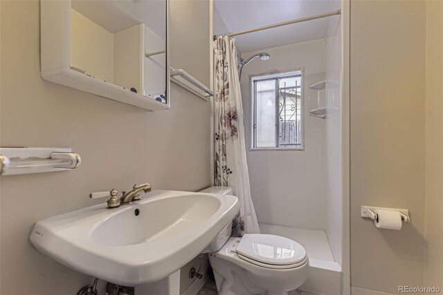 full bathroom featuring curtained shower, a sink, and toilet