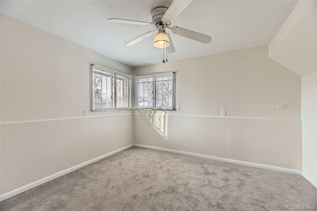 carpeted empty room featuring a ceiling fan and baseboards