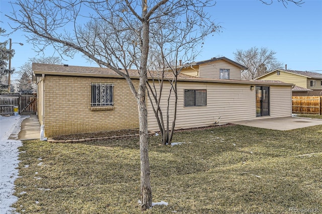 back of property featuring a patio, brick siding, a lawn, and fence