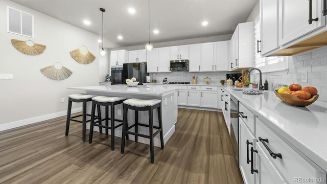 27994 E Indore Dr, Aurora, CO 80016 - kitchen with appliances with stainless steel finishes, a breakfast bar, decorative backsplash, white cabinetry, and recessed lighting