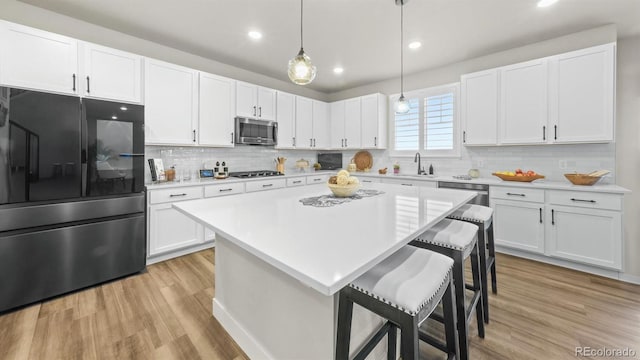 27994 E Indore Dr, Aurora, CO 80016 - kitchen featuring appliances with stainless steel finishes, light wood-style flooring, a breakfast bar area, light countertops, and tasteful backsplash