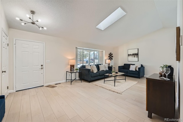 living room featuring a textured ceiling, lofted ceiling with skylight, a chandelier, and light wood-type flooring