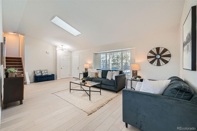 living room featuring lofted ceiling with skylight and light hardwood / wood-style floors