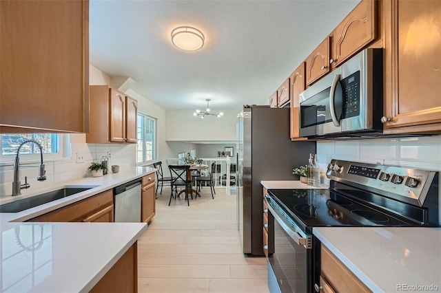 kitchen featuring decorative light fixtures, sink, decorative backsplash, stainless steel appliances, and an inviting chandelier