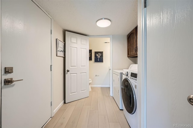 clothes washing area featuring cabinets, independent washer and dryer, a textured ceiling, and light wood-type flooring