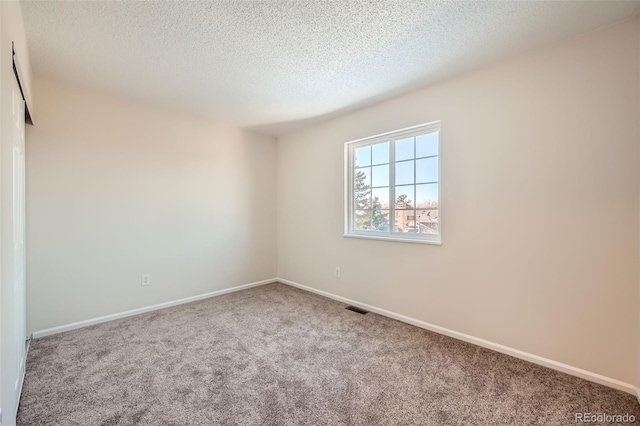 carpeted empty room featuring a textured ceiling