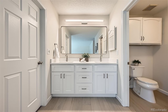 bathroom featuring vanity, a textured ceiling, toilet, and hardwood / wood-style flooring