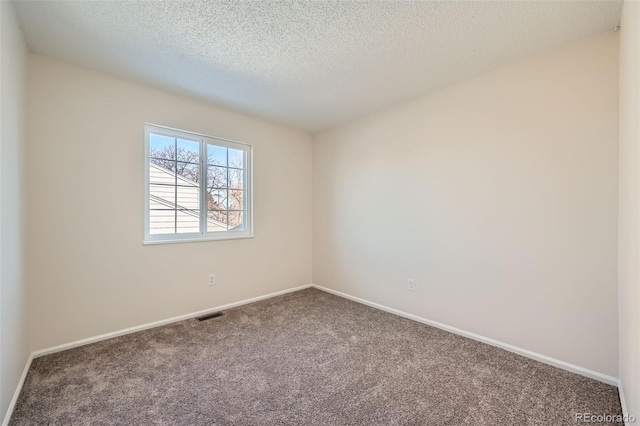 empty room with carpet floors and a textured ceiling