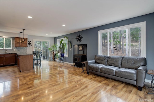 living room featuring light wood-style floors, baseboards, a wood stove, and recessed lighting