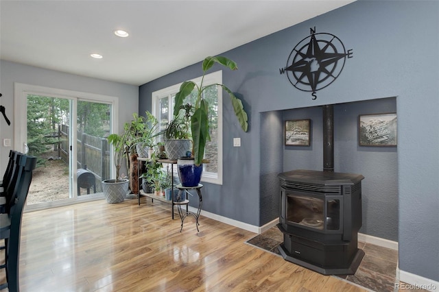 interior space with recessed lighting, baseboards, wood finished floors, and a wood stove