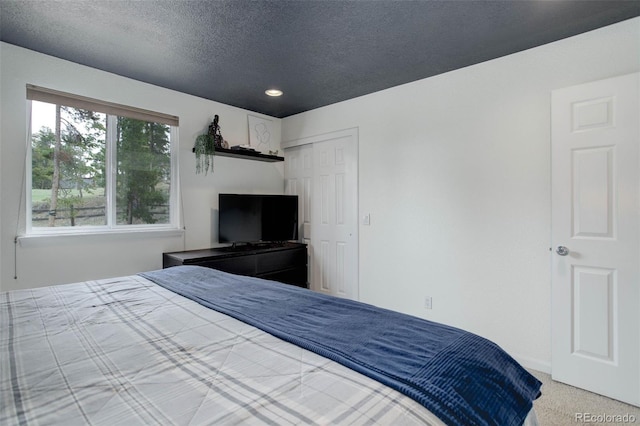 carpeted bedroom with recessed lighting, a textured ceiling, and a closet