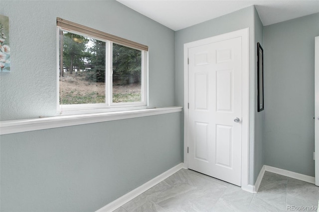 unfurnished bedroom featuring baseboards and marble finish floor