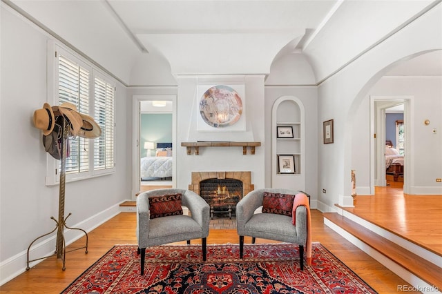 810 Milwaukee St, Denver, CO 80206 - sitting room featuring light wood-type flooring, arched walkways, a fireplace, and built in shelves