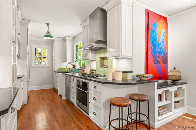 810 Milwaukee St, Denver, CO 80206 - kitchen with stainless steel appliances, wall chimney range hood, white cabinets, and light wood-type flooring