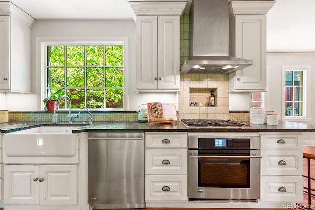 810 Milwaukee St, Denver, CO 80206 - kitchen with appliances with stainless steel finishes, wall chimney range hood, tasteful backsplash, white cabinets, and crown molding