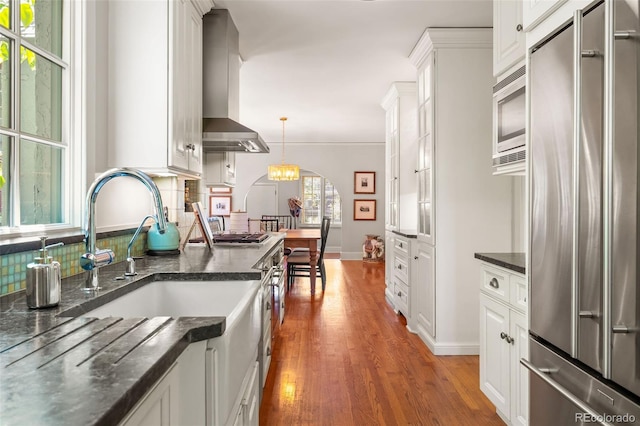 810 Milwaukee St, Denver, CO 80206 - kitchen with appliances with stainless steel finishes, wood finished floors, white cabinetry, and arched walkways