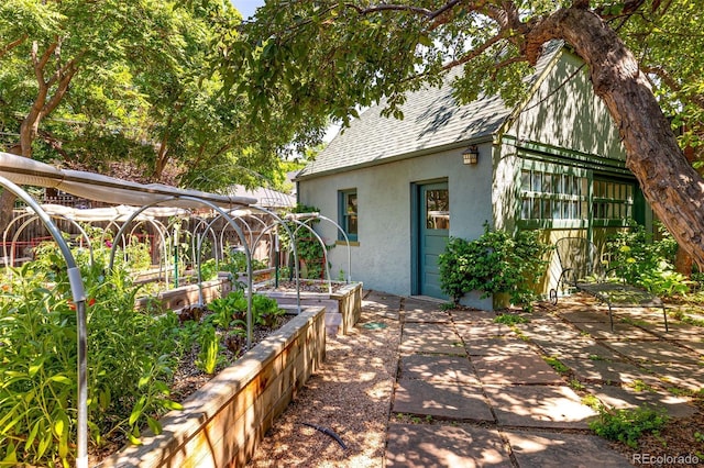 810 Milwaukee St, Denver, CO 80206 - view of home's exterior with stucco siding, a shingled roof, a vegetable garden, and a patio