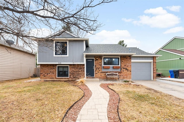 tri-level home featuring roof with shingles, concrete driveway, a front lawn, a garage, and brick siding