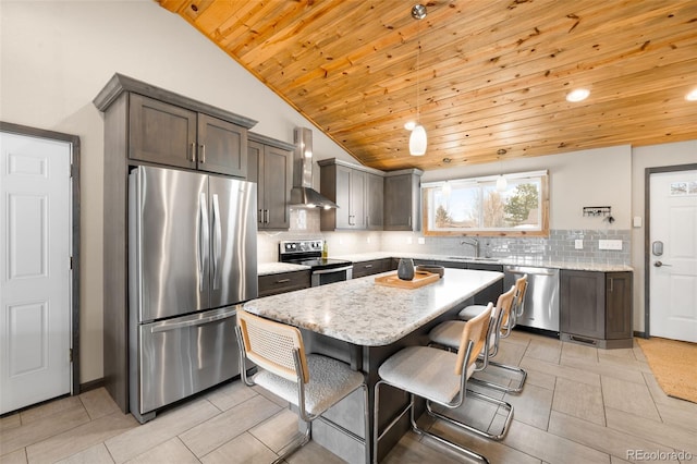 kitchen featuring a kitchen island, lofted ceiling, a sink, appliances with stainless steel finishes, and wall chimney range hood