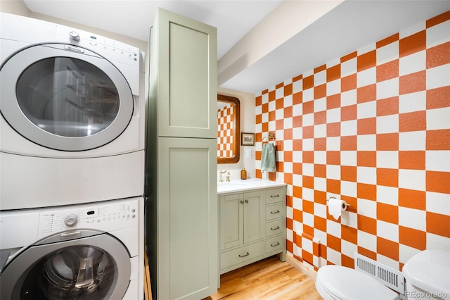 laundry area featuring visible vents, light wood-type flooring, stacked washer and dryer, a sink, and laundry area