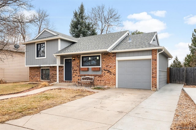 tri-level home featuring a garage, roof with shingles, driveway, and fence