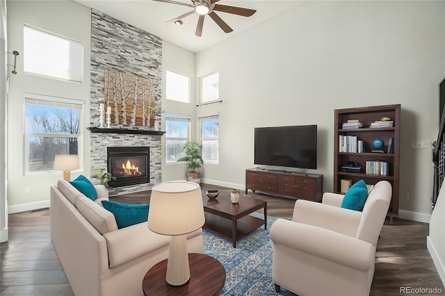 living room with a fireplace, a towering ceiling, dark hardwood / wood-style floors, and ceiling fan