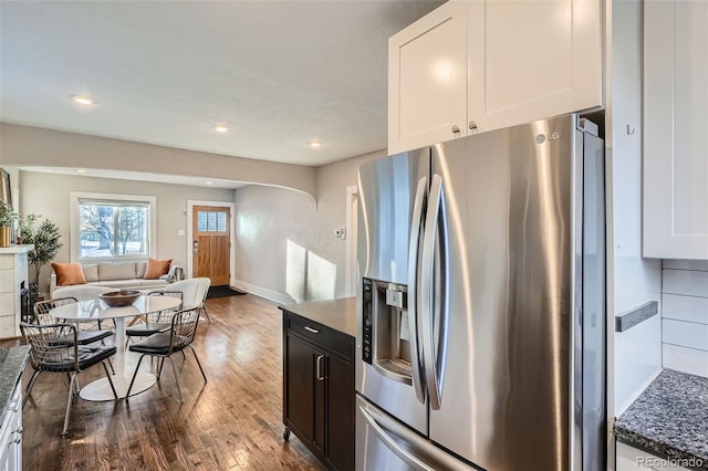 kitchen featuring white cabinetry, stainless steel refrigerator with ice dispenser, hardwood / wood-style floors, and dark stone counters