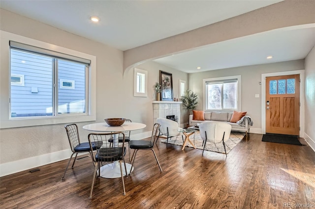 dining area with a tiled fireplace and dark hardwood / wood-style floors