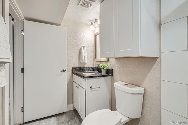 bathroom featuring vanity, a textured ceiling, and toilet