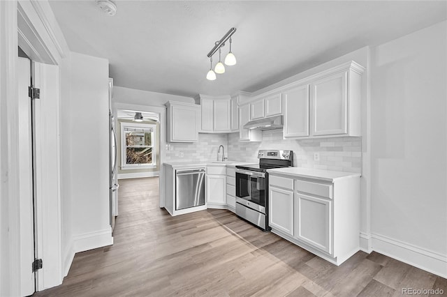 kitchen featuring stainless steel appliances, light countertops, white cabinetry, a sink, and under cabinet range hood