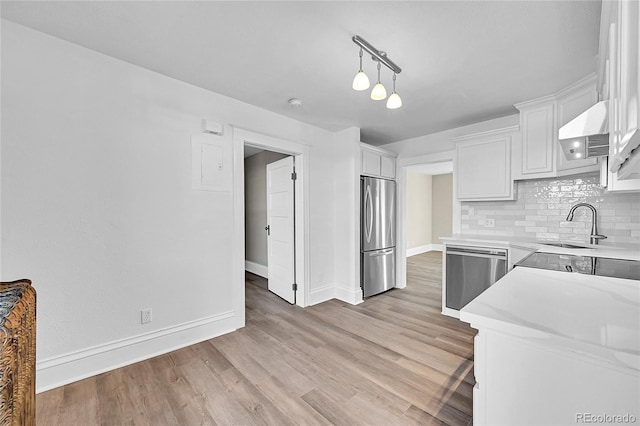 kitchen featuring tasteful backsplash, light hardwood / wood-style flooring, appliances with stainless steel finishes, pendant lighting, and white cabinets